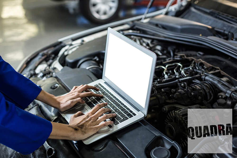 mani che scrivono su un computer collegato ad un motore di una macchina