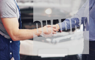 persone che si stringono la mano in un'officina meccanica