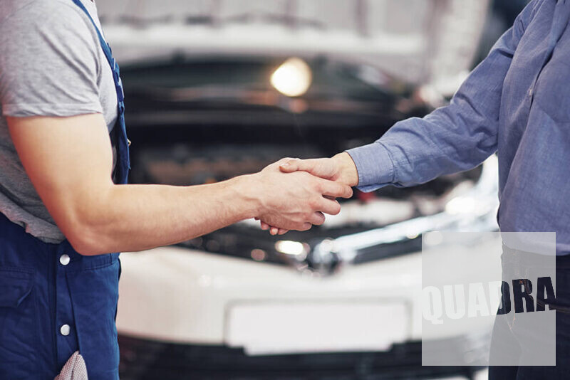 persone che si stringono la mano in un'officina meccanica